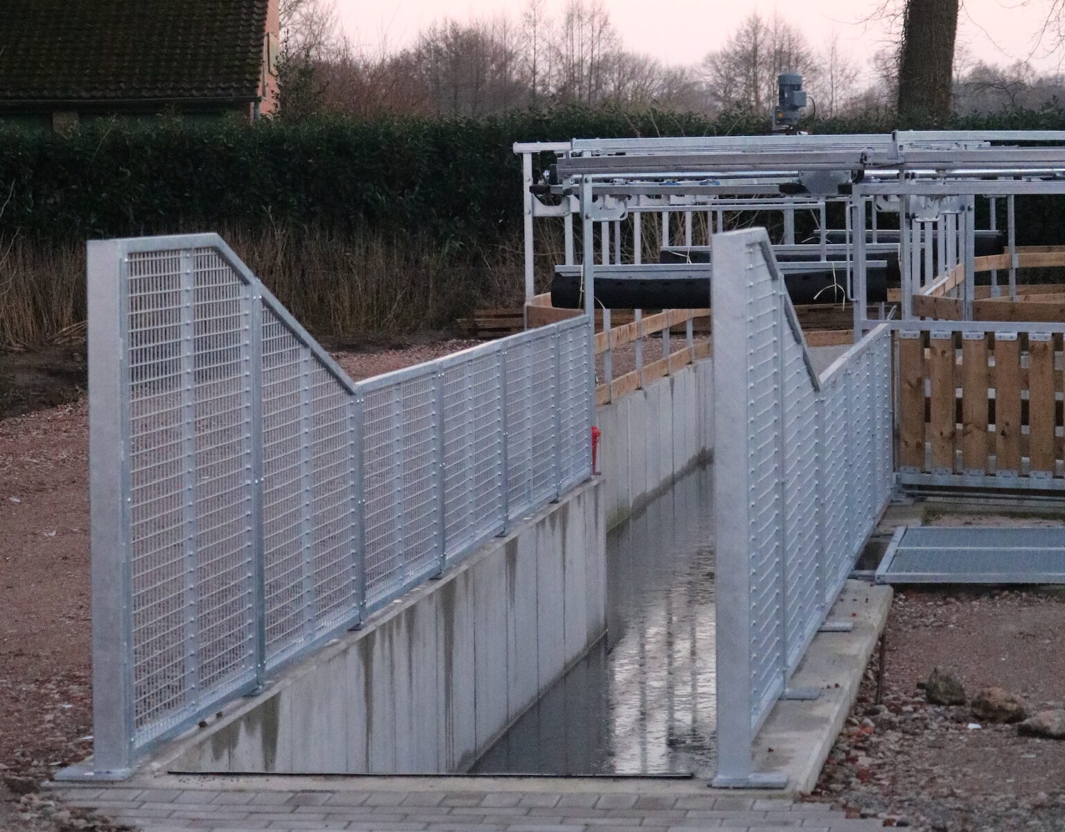 Moderne Wasserführanlage für Pferde mit metallenen Leitgittern und einem Wasserlauf im Außenbereich.