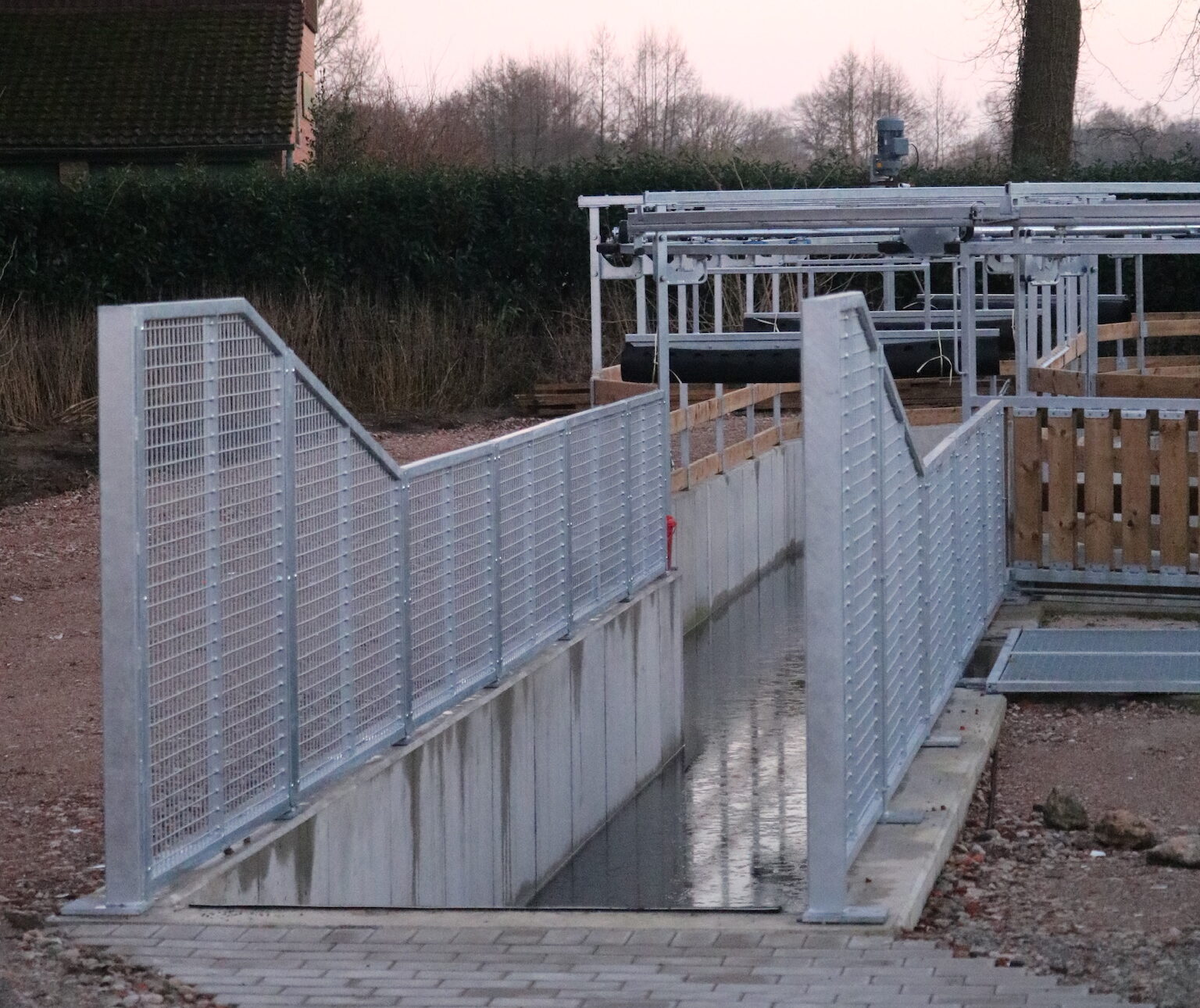 Moderne Wasserführanlage für Pferde mit metallenen Leitgittern und einem Wasserlauf im Außenbereich.